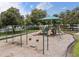 View of a neighborhood playground featuring swings, slides, and a climbing area within a fenced, landscaped space at 1827 Trillium Blvd, Brooksville, FL 34604
