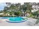 Community pool with lounge chairs surrounded by lush greenery and mature trees at 1830 Cypress Trace Dr, Safety Harbor, FL 34695
