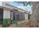 Rear exterior view of the home with large windows, a screened-in porch, and mature landscaping at 1830 Cypress Trace Dr, Safety Harbor, FL 34695