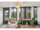 Relaxing sunroom features a comfortable chair, lush plants, and panoramic views of the landscaped backyard at 1830 Cypress Trace Dr, Safety Harbor, FL 34695