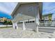 Street view of a home with large garage spaces, brick-paved driveway, and upper-floor porch access at 19111 Whispering Pines Dr, Indian Shores, FL 33785