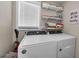 Laundry room featuring modern washer and dryer with shelving, offering convenience and organization at 19111 Whispering Pines Dr, Indian Shores, FL 33785
