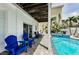 An outdoor patio showcasing blue chairs, a nearby spa, and lush tropical landscaping at 19111 Whispering Pines Dr, Indian Shores, FL 33785