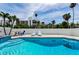 Inviting pool area featuring lounge chairs and a glimpse of nearby buildings and palm trees at 19111 Whispering Pines Dr, Indian Shores, FL 33785