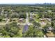 An aerial view of a quiet neighborhood filled with lush green trees and well-maintained homes, with a city skyline in the distance at 1914 E Chelsea St, Tampa, FL 33610