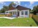 Delightful home featuring a charming front porch, lush green lawn, and modern fencing at 1914 E Chelsea St, Tampa, FL 33610