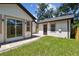 An exterior view featuring a paver walkway, lush green grass, a modern exterior, and a detached garage at 1914 E Chelsea St, Tampa, FL 33610