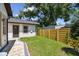 An exterior view shows lush green grass, a modern exterior, a horizontal wood fence, and a detached garage at 1914 E Chelsea St, Tampa, FL 33610