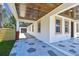 Spacious front porch leading to a detached garage, featuring a decorative floor and wood plank ceiling at 1914 E Chelsea St, Tampa, FL 33610