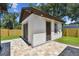Exterior view of the detached garage with a brown garage door, stone accents, and lush lawn at 1914 E Chelsea St, Tampa, FL 33610