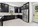 Modern kitchen featuring stainless steel appliances, black cabinets, white countertops, and herringbone backsplash at 1914 E Chelsea St, Tampa, FL 33610