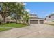This two-story home features a three car garage, manicured lawn, and mature trees at 21108 Bircholm Ct, Land O Lakes, FL 34637