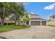 This two-story home features a three car garage, manicured lawn, and mature trees at 21108 Bircholm Ct, Land O Lakes, FL 34637
