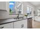 Modern kitchen showcasing a sink, stainless steel dishwasher, and view of outdoor enclosed lanai and swimming pool at 21108 Bircholm Ct, Land O Lakes, FL 34637
