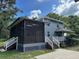 Exterior of house with screened in porch, white railing, a staircase, and mature trees at 222 Spring Lake Hwy, Brooksville, FL 34602