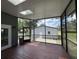 Enclosed screened porch with wood flooring and a view of the backyard and detached garage at 222 Spring Lake Hwy, Brooksville, FL 34602