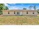 Backyard of beige single story home featuring an expansive lawn and a rear door at 2627 Hancock St, Plant City, FL 33563