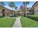 Beautiful condo exterior showcasing lush landscaping, walkways and tan buildings with stairs leading to the second floor at 2681 Sabal Springs Cir # 204, Clearwater, FL 33761