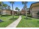Condo exterior featuring manicured lawn, a central walkway, and beautiful tan buildings with stairs at 2681 Sabal Springs Cir # 204, Clearwater, FL 33761
