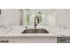 Modern white kitchen island featuring a stainless steel sink, quartz countertops, and matte black hardware at 301 S Daniels St, Plant City, FL 33563