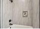 Close up on a white tub and shower with gray tiling and a decorative shelf insert at 301 S Daniels St, Plant City, FL 33563