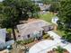 A high aerial view of a well-maintained single-story home with a circular driveway and lush backyard greenery at 3115 Bay Ln, Clearwater, FL 33759