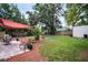 Well-maintained backyard featuring a patio area with shade sail, garden beds, and mature trees at 3115 Bay Ln, Clearwater, FL 33759