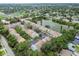 Aerial view showcases colorful townhomes nestled among trees with a serene lake nearby at 3308 W Wyoming Cir, Tampa, FL 33611