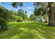 Spacious backyard with green lawn, mature trees, and charming shed at 4537 Thornton Dr, Zephyrhills, FL 33542
