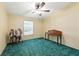 Bright bedroom with green carpet, ceiling fan, and writing desk providing a comfortable space at 4537 Thornton Dr, Zephyrhills, FL 33542