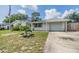 Inviting home exterior with a manicured lawn, shade tree, and convenient driveway access to the attached garage at 5414 Oceanic Rd, Holiday, FL 34690