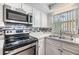 Well-lit kitchen featuring stainless steel appliances, mosaic backsplash, and double basin sink at 5414 Oceanic Rd, Holiday, FL 34690