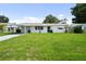Charming single-story home features a carport, a green lawn and a bright green front door at 5627 57Th N Ave, St Petersburg, FL 33709