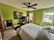 Bright bedroom featuring a ceiling fan, two windows, and green colored walls at 6781 121St Ave # H, Largo, FL 33773