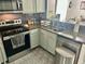 Well-lit kitchen featuring stainless steel appliances, granite countertops, and gray cabinets at 6781 121St Ave # H, Largo, FL 33773