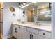 Modern bathroom featuring a double vanity, large mirror, and a walk-in shower with neutral tiling at 7683 Summerland Cv, Lakewood Ranch, FL 34202