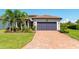Beautiful home showcasing a brick driveway, tile roof, and tropical landscaping at 7683 Summerland Cv, Lakewood Ranch, FL 34202
