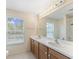 Bright bathroom featuring a double sink vanity, large mirror, and a window offering natural light at 8222 Haven Harbour Way, Bradenton, FL 34212