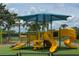 A close-up of the yellow playground with multiple slides, stairs, and play stations under a blue sunshade at 8222 Haven Harbour Way, Bradenton, FL 34212