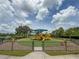 Fenced playground with yellow slides and play structures, wood chip ground cover, and lush green grass at 8222 Haven Harbour Way, Bradenton, FL 34212