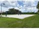Brightly lit white sand volleyball court is surrounded by vibrant green grass and tall palm trees at 8222 Haven Harbour Way, Bradenton, FL 34212