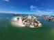 Panoramic aerial view of waterfront condo community with pool, sandy beach and bay access under sunny skies at 855 Bayway Blvd # 908, Clearwater Beach, FL 33767