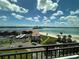 Balcony view showcasing sandy beaches, serene ocean waters, city buildings, and a bright cloudy sky at 855 Bayway Blvd # 908, Clearwater Beach, FL 33767