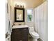 Cozy bathroom with dark wood vanity, window view and shower with white curtain at 878 Franklin Cir, Palm Harbor, FL 34683