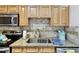 Kitchen featuring stainless sink, granite counters, tile backsplash and stainless appliances at 878 Franklin Cir, Palm Harbor, FL 34683