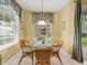 A sunny breakfast nook with a glass table and four wicker chairs, next to a large window at 897 Lantern Way, Clearwater, FL 33765