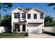 New construction home with white siding, black trim, two-car garage, and a stone base at 905 N Willow Ave, Tampa, FL 33606
