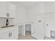 A well-lit laundry room featuring white cabinetry, a sink, and ample countertop space, perfect for chores at 905 N Willow Ave, Tampa, FL 33606