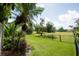 Spacious backyard featuring lush green grass, mature trees, and a fence overlooking a golf course at 916 Bunker View Dr, Apollo Beach, FL 33572