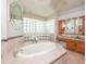 Bright bathroom featuring a large oval tub, glass block shower, and oak vanity with granite countertop at 916 Bunker View Dr, Apollo Beach, FL 33572